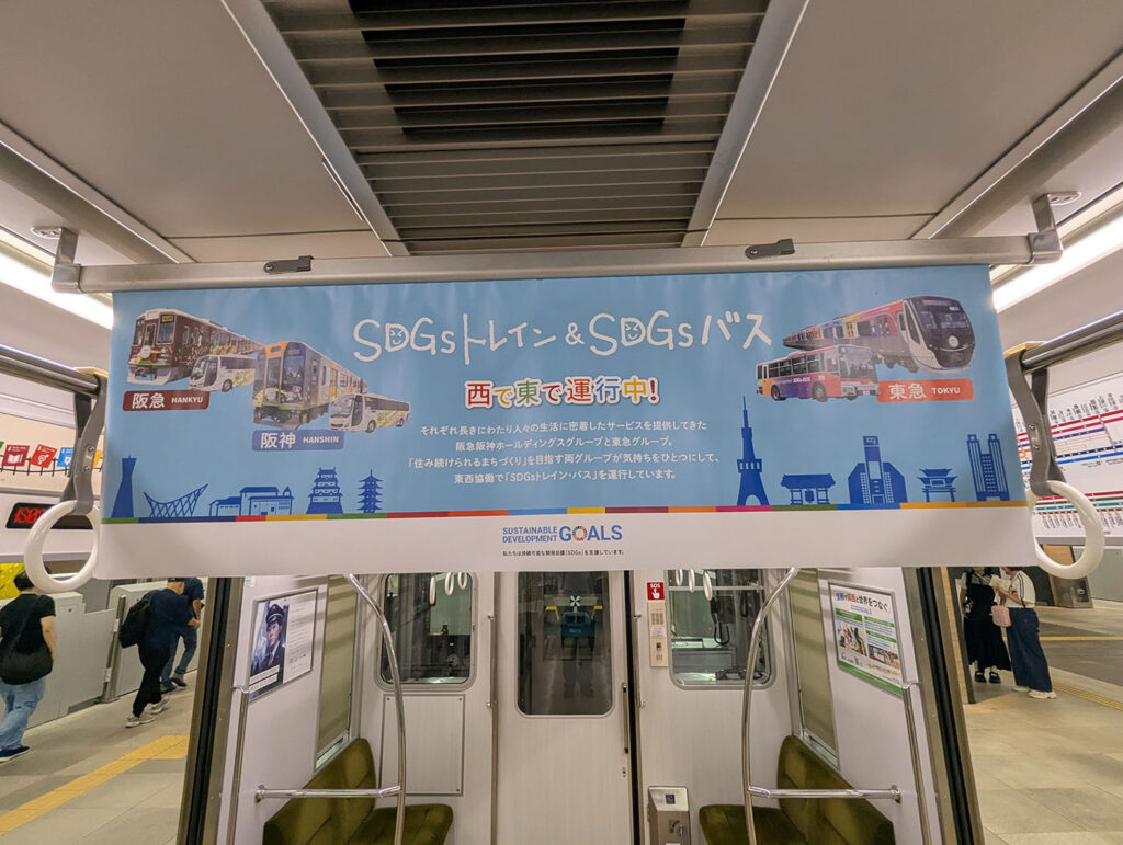 「SDGsトレイン＆SDGsバス」の吊り広告。阪急・阪神・東急の電車とバスのイラストが並び、西と東で運行中であることを紹介している。